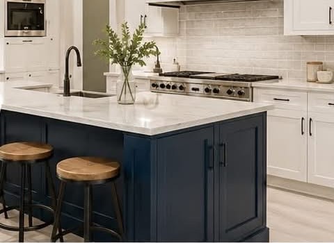 Remodeled white kitchen with a navy island, marble countertop and wood bar stools